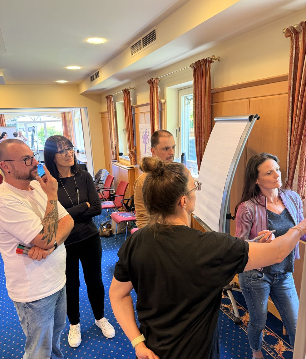 Lehrgangsgruppe arbeitet gemeinsam am Flipchart im Seminarraum